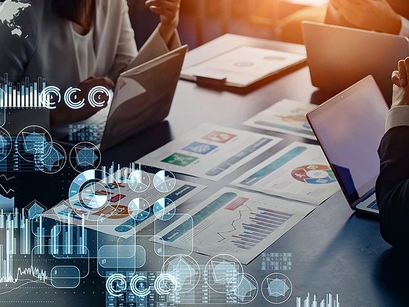 Drei Personen sitzen mit ihren Laptops an einem Tisch