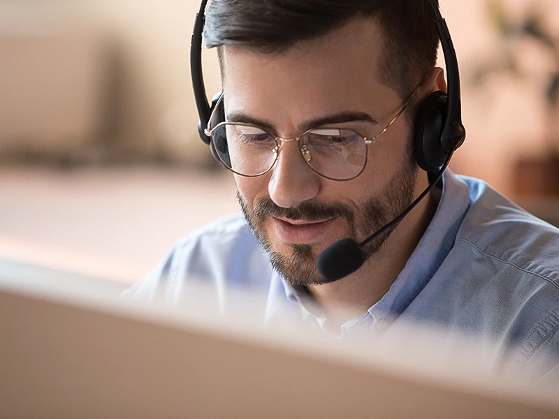 Ein Service-Mitarbeiter hält ein Support-Gespräch am Telefon über Headset.