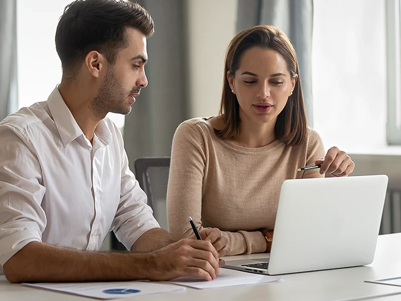 Un homme et une femme travaillent ensemble sur un ordinateur portable.