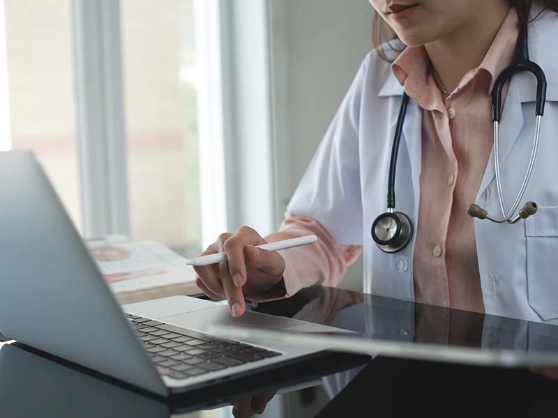 Eine Ärztin prüft die Vorsorge-Übersicht am Laptop.
