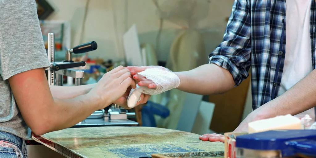 Eine Person verbindet einer anderen Person die verletze Hand.