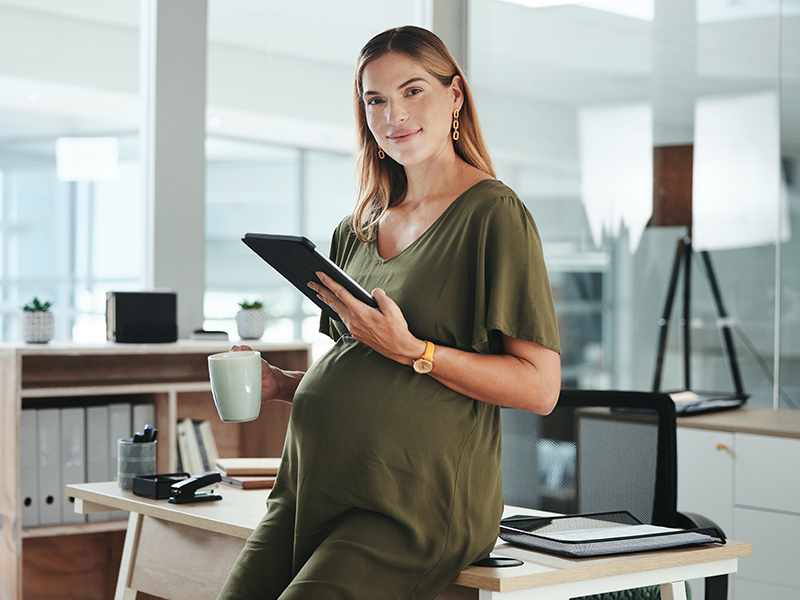 Schwangere Frau mit einem Tablet in der Hand.