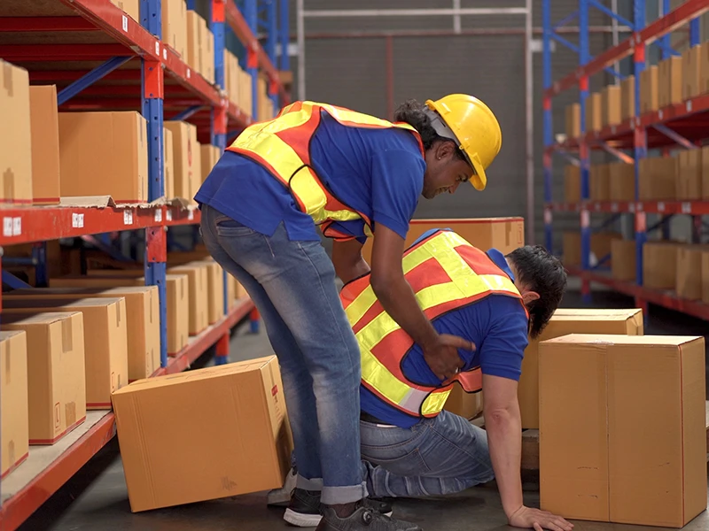 Ein Lagermitarbeiter hilft seinem Kollegen nach einem Unfall