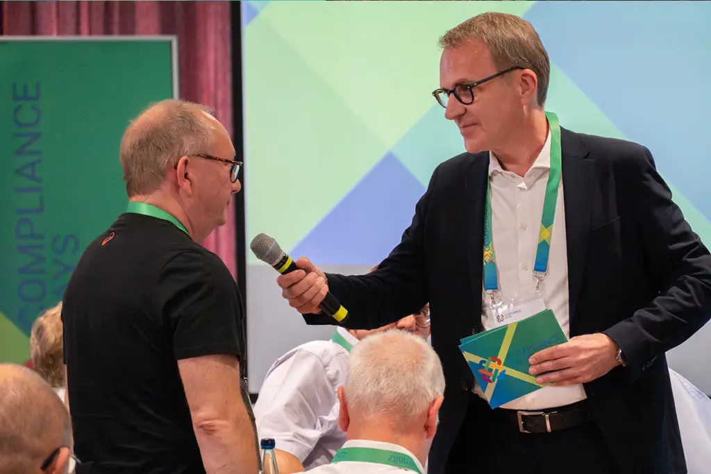 Redner Frederec Lau reicht einem Gast das Mikrofon.