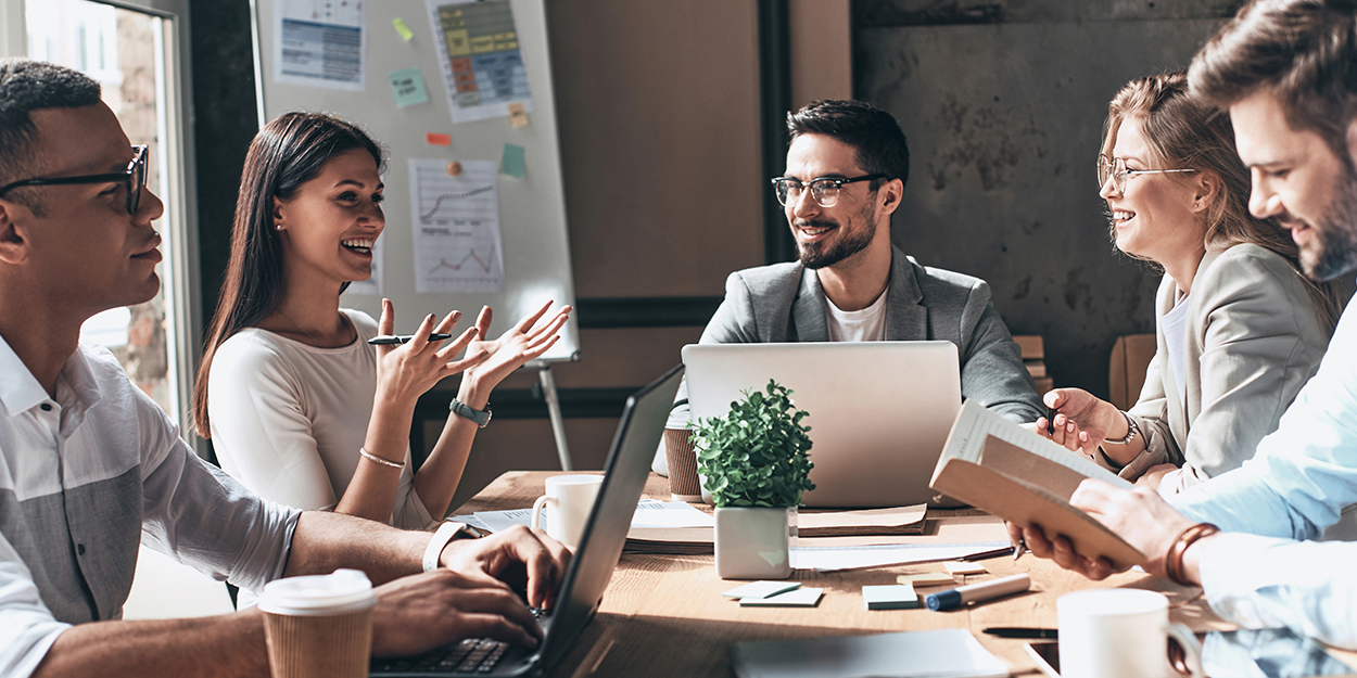 Ein glückliches Team arbeitet gemeinsam an Laptops