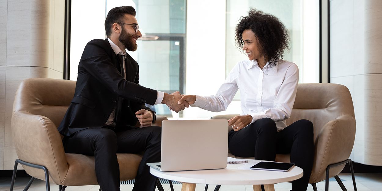 Zwei Mitarbeitende schütteln sich freundlich die Hand