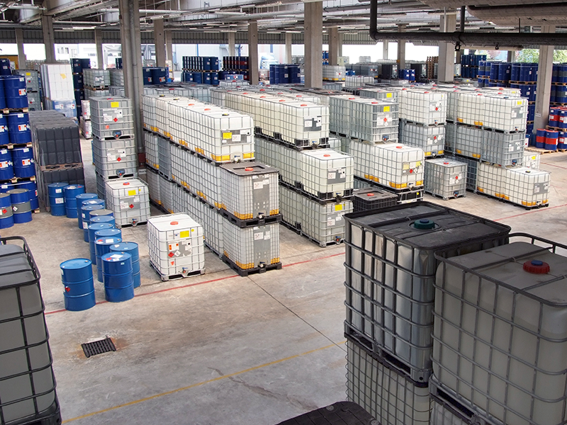 Eine Lagerhalle mit großen übereinandergestapelten Kanistern. 