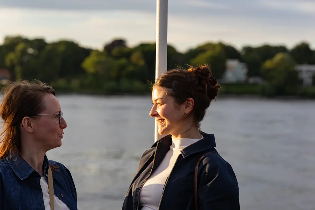 Zwei Personen unterhalten sich, im Hintergrund ist die Elbe zu sehen.
