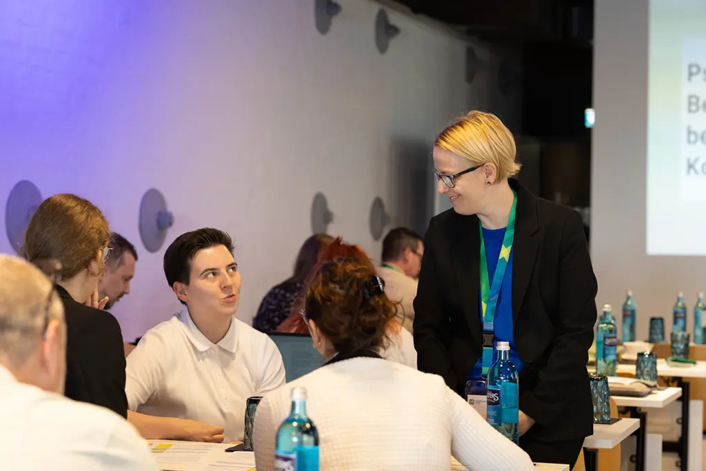 Personen sitzen am Tisch in einem Konferenzraum.