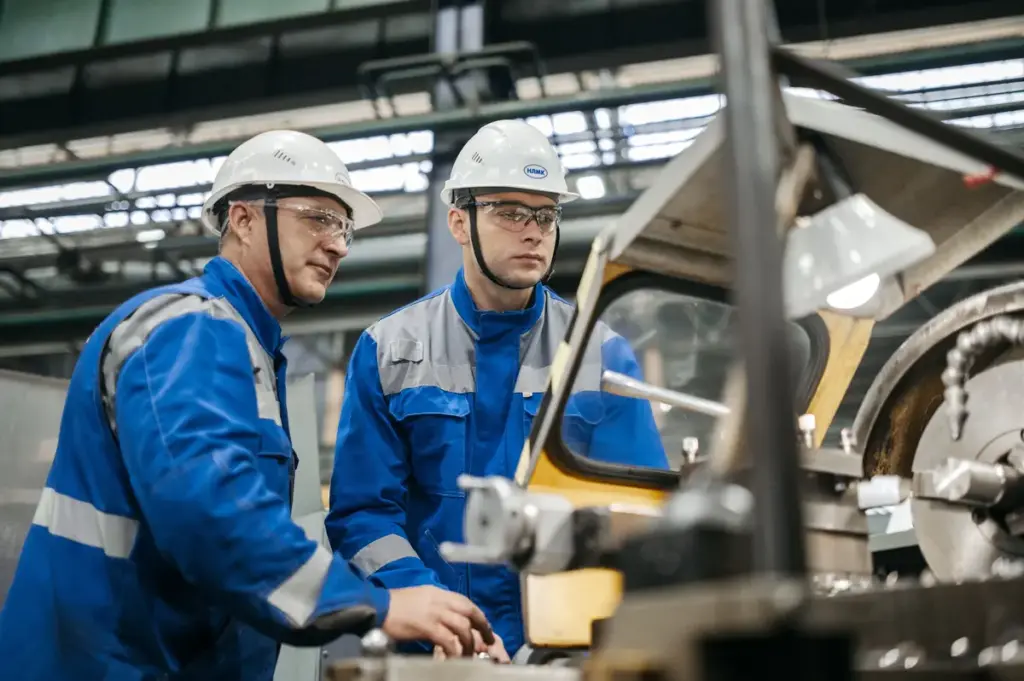 Ein Mann steht mit einem Tablet in einer Fabrikhalle.